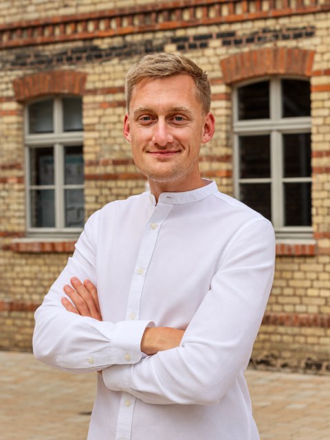 Lennart Hischer, Inhaber von Hischer Immobilien, vor einer Backsteinfassade in Brandenburg